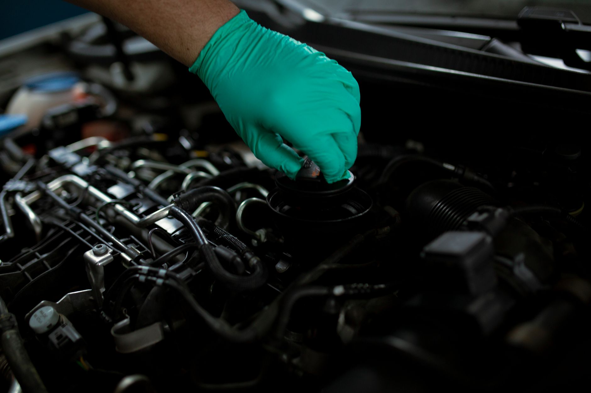 A mechanic in gloves draining engine oil on a car