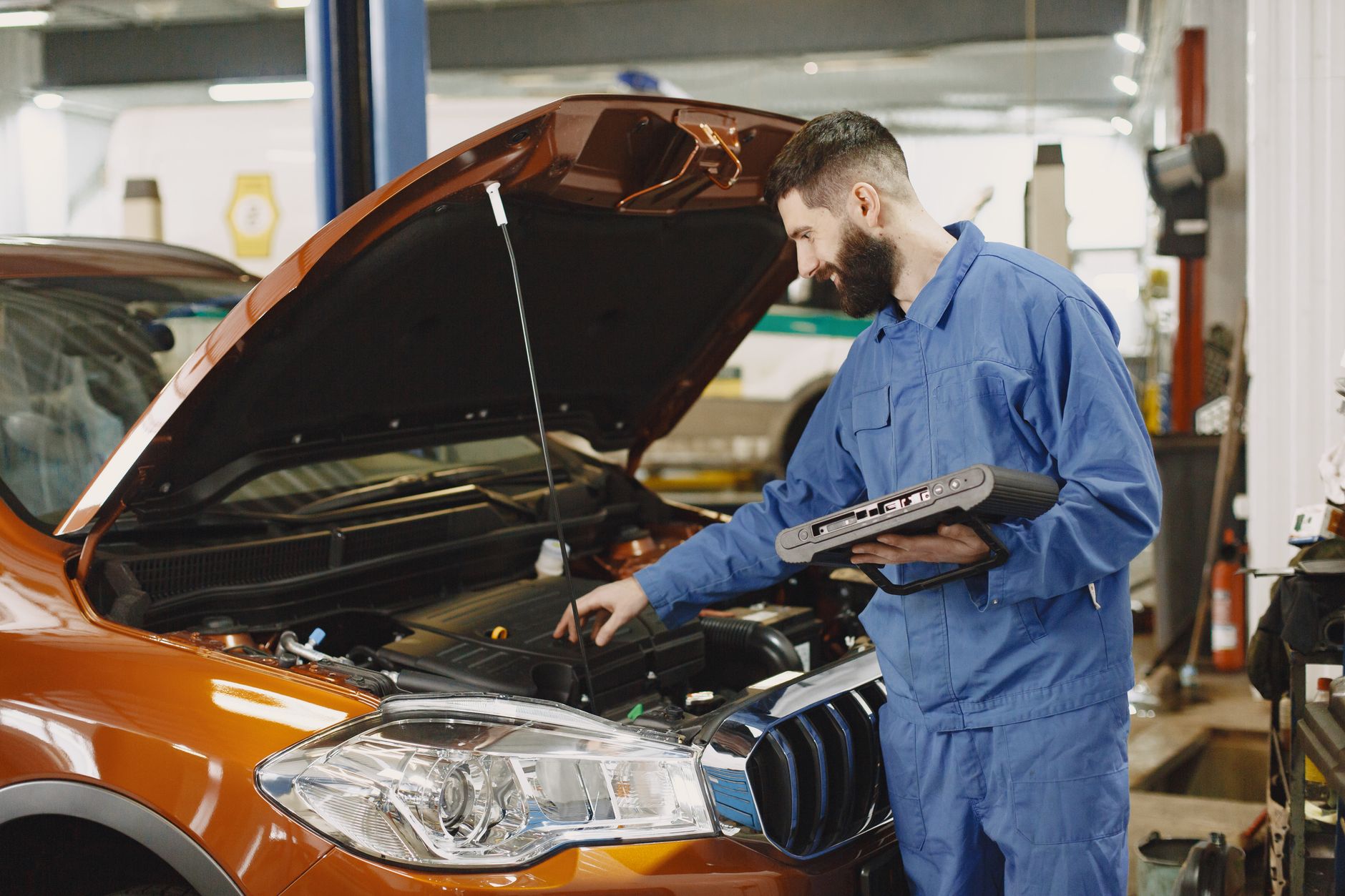 A technician running diagnostics on an engine with the hood open